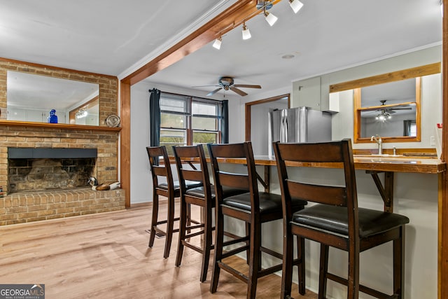 dining area featuring a fireplace, light hardwood / wood-style floors, ceiling fan, and ornamental molding