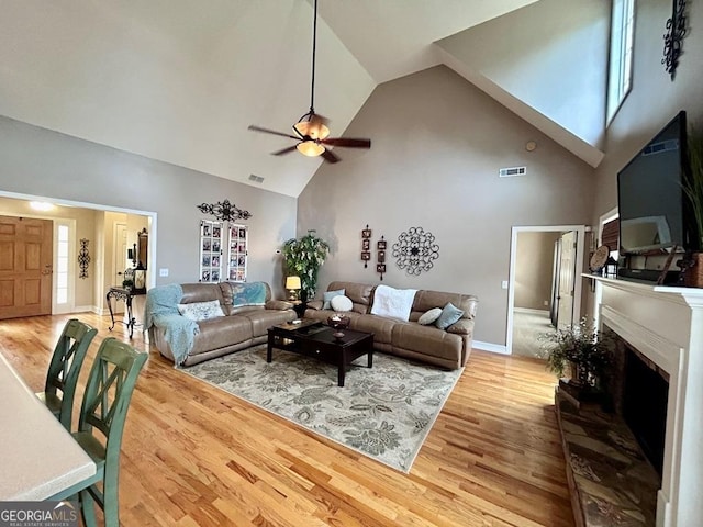 living room with ceiling fan, high vaulted ceiling, and light hardwood / wood-style floors