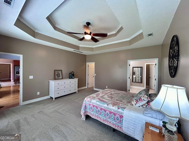 bedroom with ornamental molding, light colored carpet, a raised ceiling, and ceiling fan