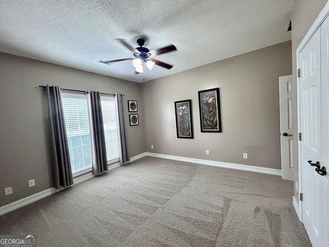 empty room featuring ceiling fan, carpet flooring, and a textured ceiling