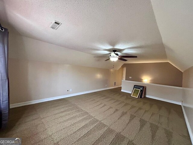 bonus room with lofted ceiling, ceiling fan, dark carpet, and a textured ceiling