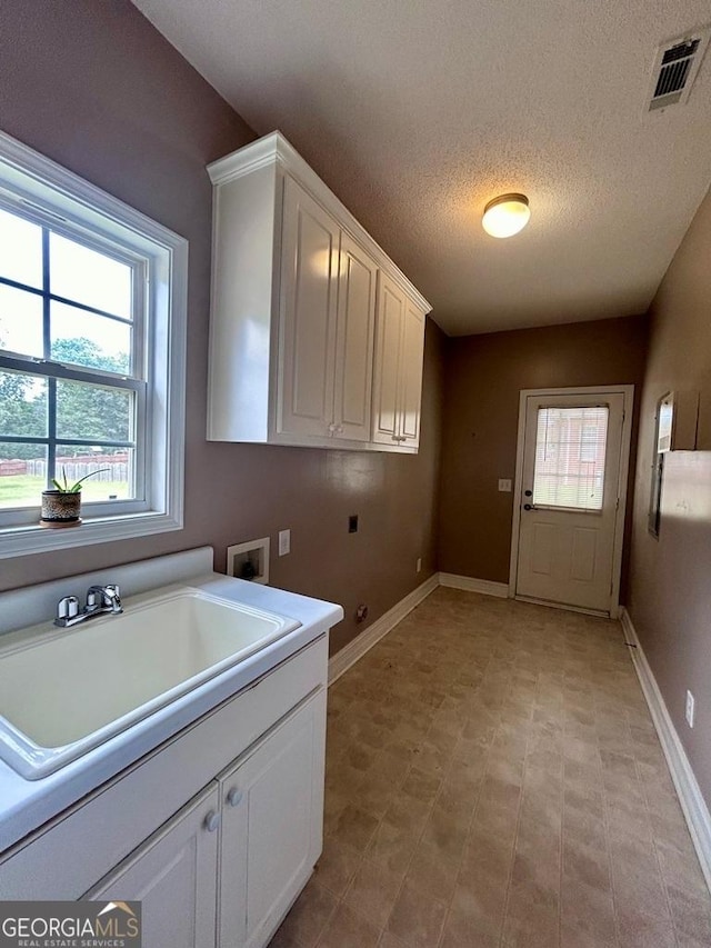 washroom with sink, cabinets, washer hookup, hookup for an electric dryer, and a textured ceiling