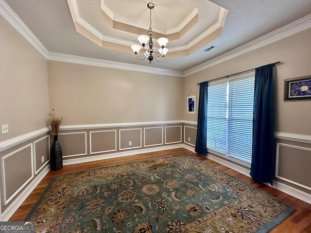 spare room with a raised ceiling, dark wood-type flooring, a textured ceiling, and a chandelier