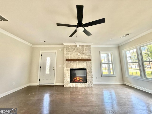 unfurnished living room featuring ceiling fan, a stone fireplace, crown molding, and dark hardwood / wood-style flooring