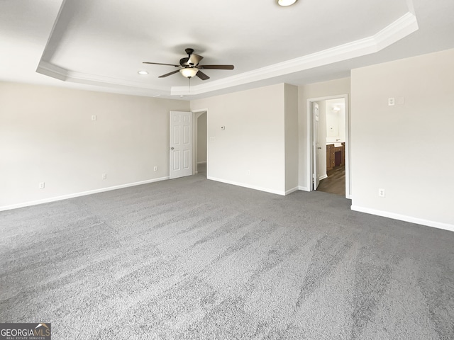 unfurnished room featuring a raised ceiling, crown molding, dark colored carpet, and ceiling fan