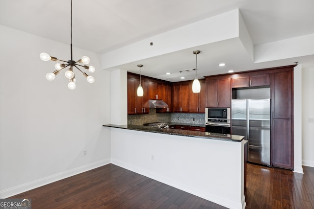 kitchen featuring hanging light fixtures, kitchen peninsula, backsplash, appliances with stainless steel finishes, and dark hardwood / wood-style floors