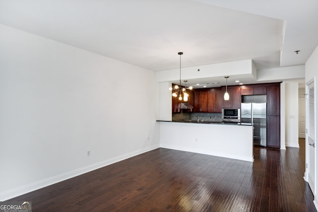 interior space with kitchen peninsula, hanging light fixtures, an inviting chandelier, backsplash, and appliances with stainless steel finishes