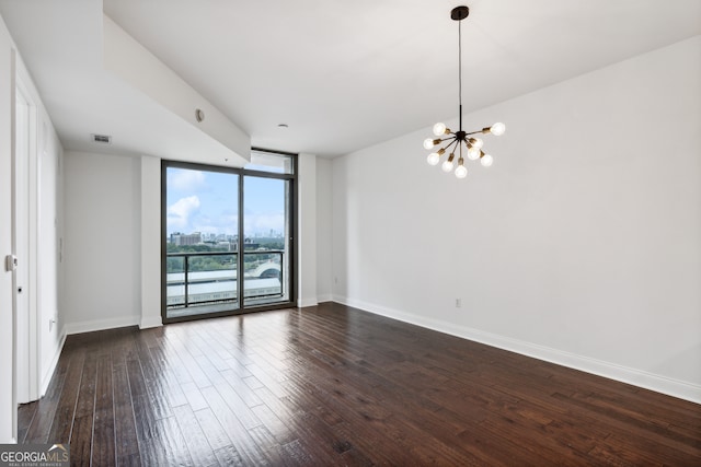 empty room with floor to ceiling windows, dark hardwood / wood-style flooring, and a notable chandelier