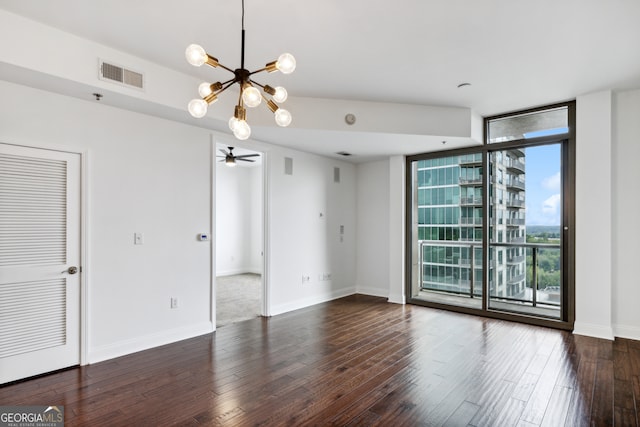 spare room with ceiling fan with notable chandelier and dark hardwood / wood-style floors