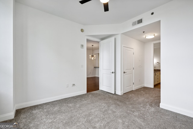 unfurnished bedroom featuring carpet floors, ceiling fan with notable chandelier, and ensuite bath