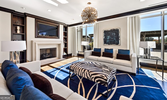 living room featuring built in shelves, hardwood / wood-style flooring, crown molding, and a chandelier