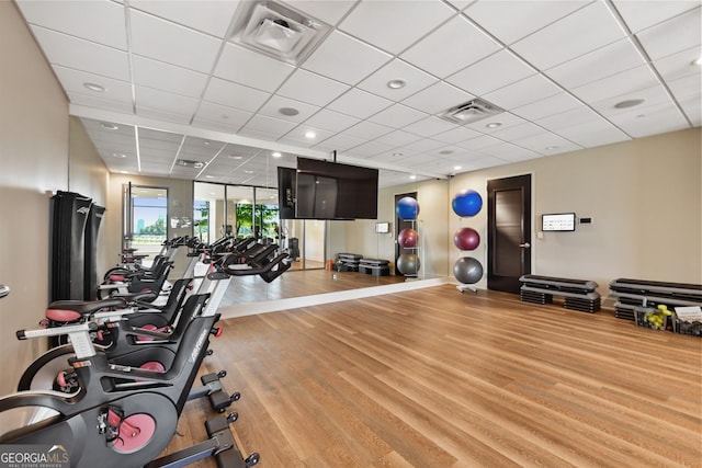 exercise room featuring light wood-type flooring and a paneled ceiling