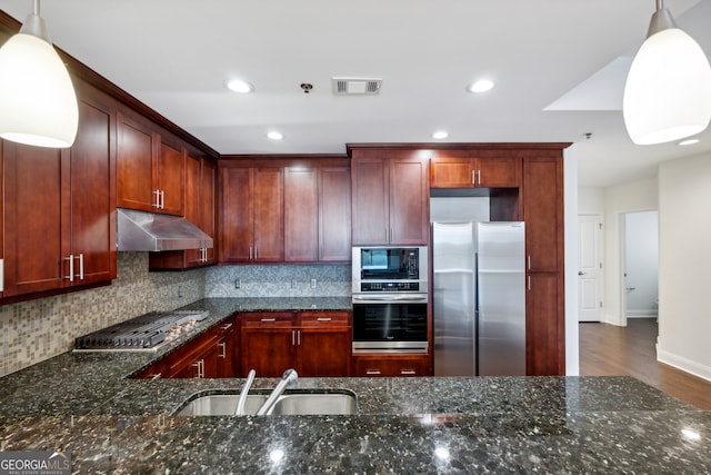 kitchen with dark stone counters, stainless steel appliances, and decorative light fixtures