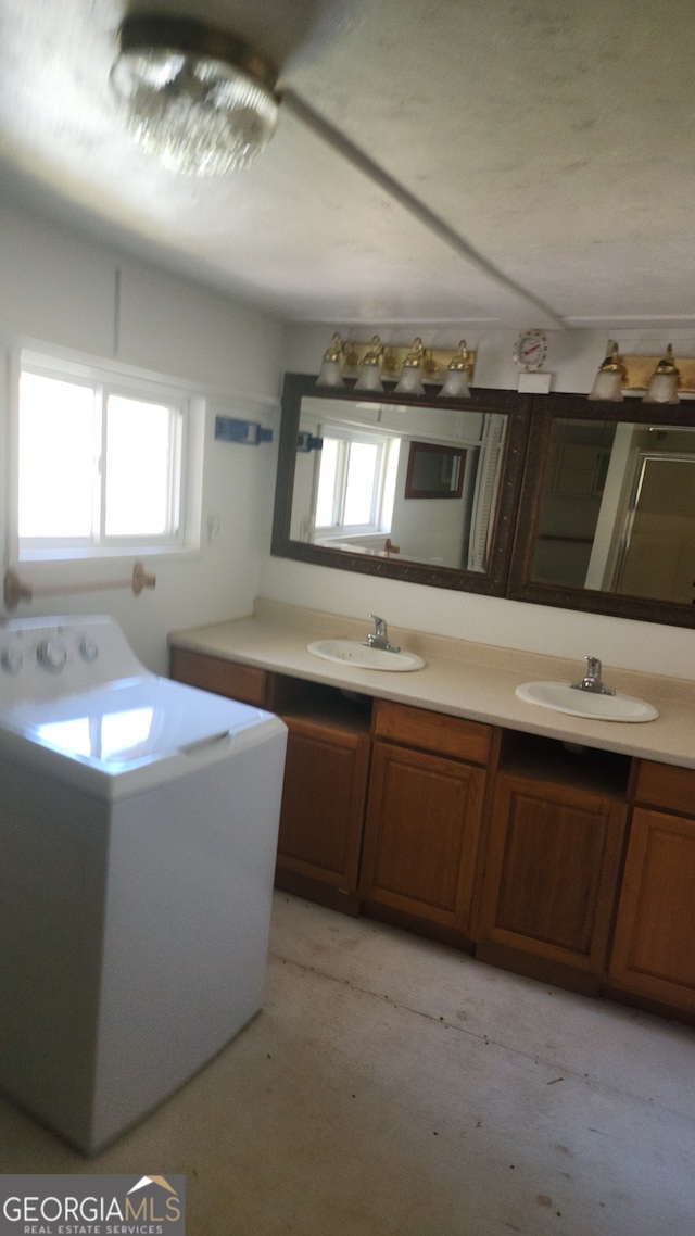 washroom with washer / clothes dryer, cabinets, and sink