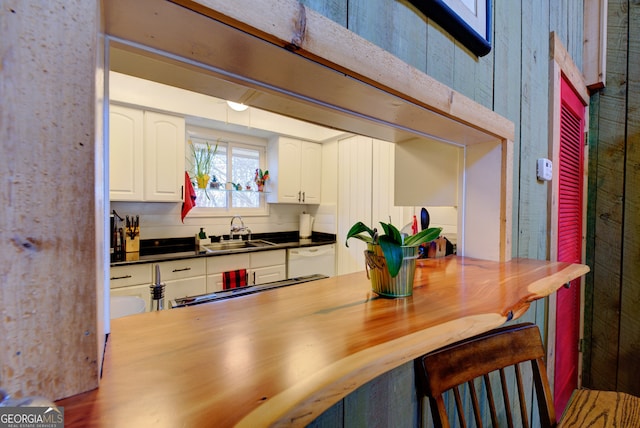 kitchen with white cabinetry, sink, and white dishwasher