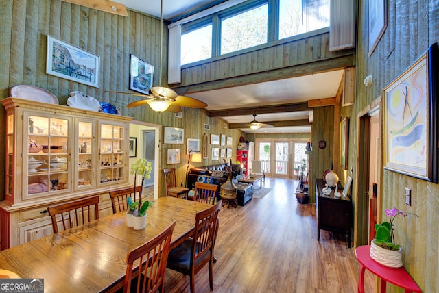 dining area with a high ceiling, beam ceiling, hardwood / wood-style floors, and ceiling fan