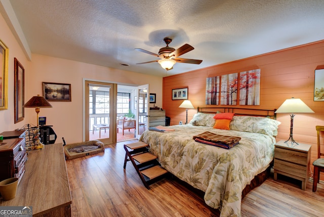 bedroom featuring ceiling fan, a textured ceiling, light hardwood / wood-style floors, and access to exterior