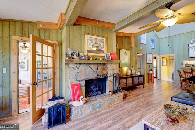 living room with wooden walls, a fireplace, hardwood / wood-style floors, and vaulted ceiling with beams