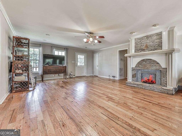 unfurnished living room with ceiling fan, crown molding, hardwood / wood-style floors, and a stone fireplace