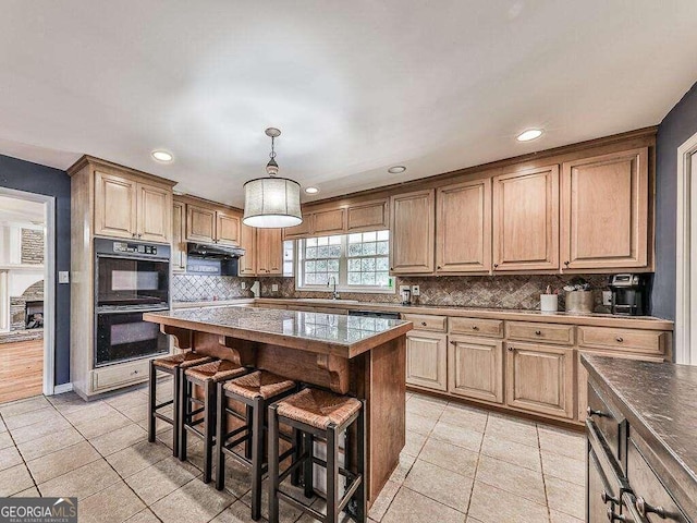 kitchen featuring a breakfast bar, a center island, hanging light fixtures, backsplash, and double oven