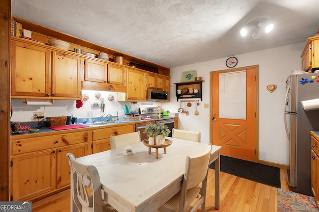 kitchen with light hardwood / wood-style flooring, a textured ceiling, appliances with stainless steel finishes, and sink