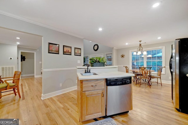 kitchen featuring appliances with stainless steel finishes, hanging light fixtures, a kitchen island with sink, and light hardwood / wood-style flooring