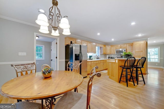 dining space with light hardwood / wood-style floors, ornamental molding, an inviting chandelier, and plenty of natural light