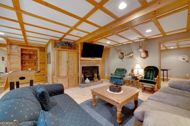 living room with coffered ceiling, beamed ceiling, built in features, and a tile fireplace