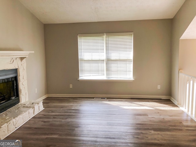 unfurnished living room with a textured ceiling, hardwood / wood-style floors, and a premium fireplace