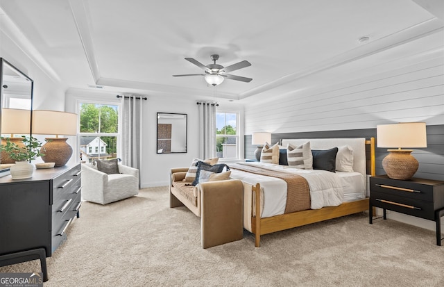 bedroom with light carpet, a raised ceiling, multiple windows, and ceiling fan