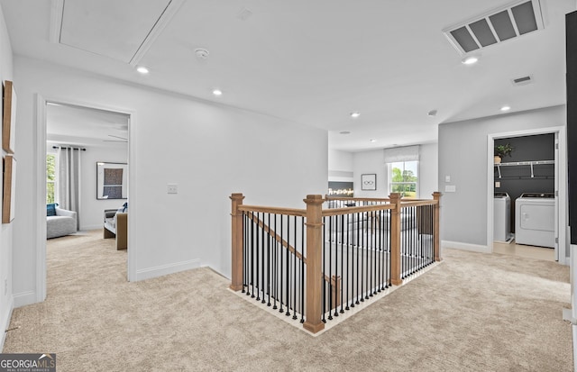 corridor with light colored carpet and washing machine and dryer