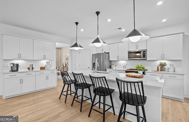 kitchen with appliances with stainless steel finishes, pendant lighting, and white cabinets