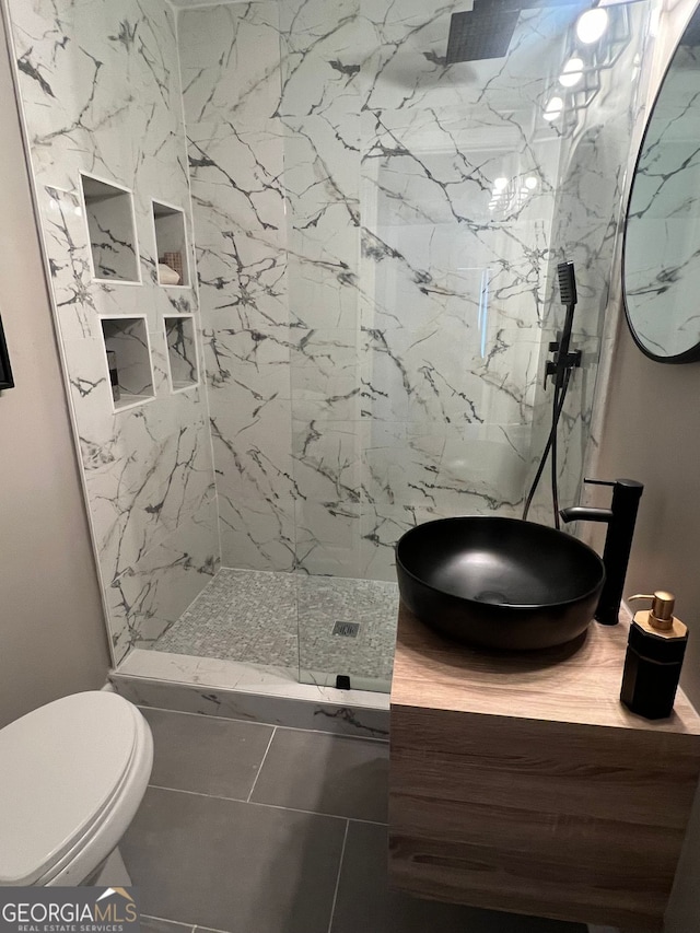 bathroom with vanity, toilet, tiled shower, a textured ceiling, and tile patterned flooring