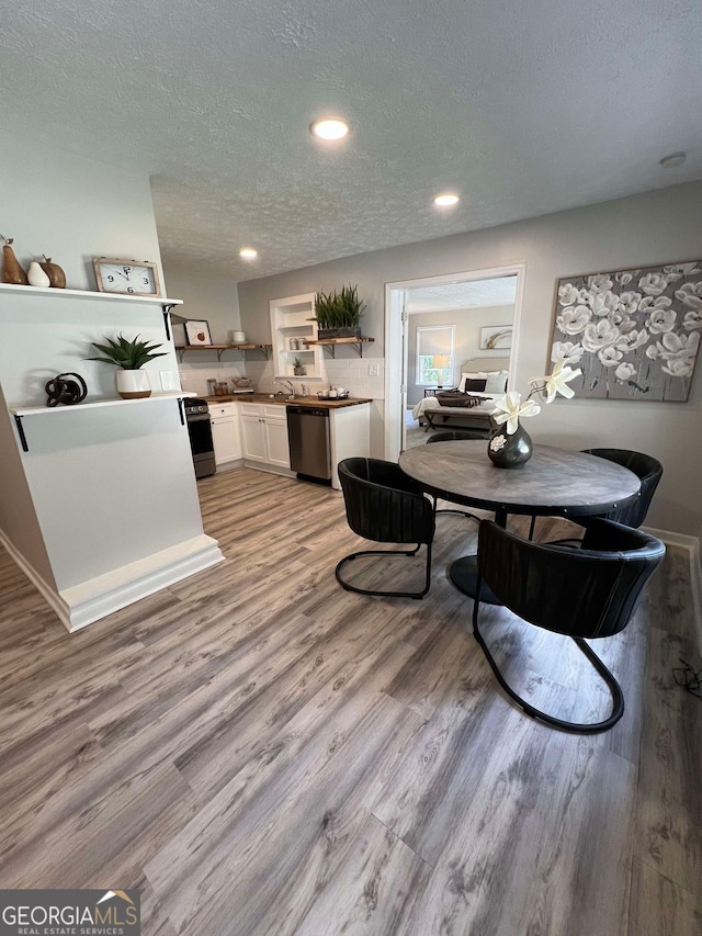 dining space with a textured ceiling, light hardwood / wood-style flooring, and sink