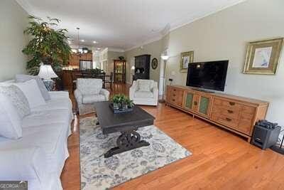 living room featuring hardwood / wood-style flooring, crown molding, and a chandelier