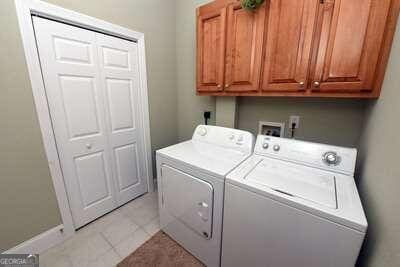 laundry room featuring cabinets, light tile patterned flooring, and washer and clothes dryer