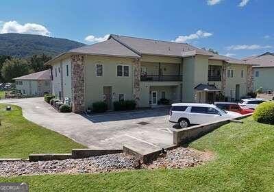 back of house with a balcony, a patio, and a lawn