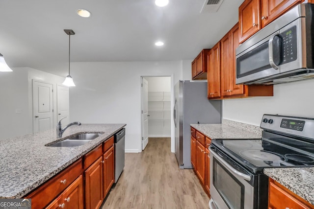 kitchen with light stone countertops, sink, stainless steel appliances, and light hardwood / wood-style floors