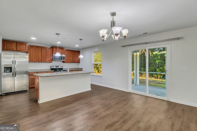 kitchen with dark wood-type flooring, a kitchen island with sink, pendant lighting, and stainless steel appliances