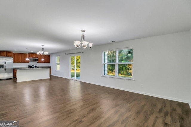 unfurnished living room with dark hardwood / wood-style floors and a notable chandelier