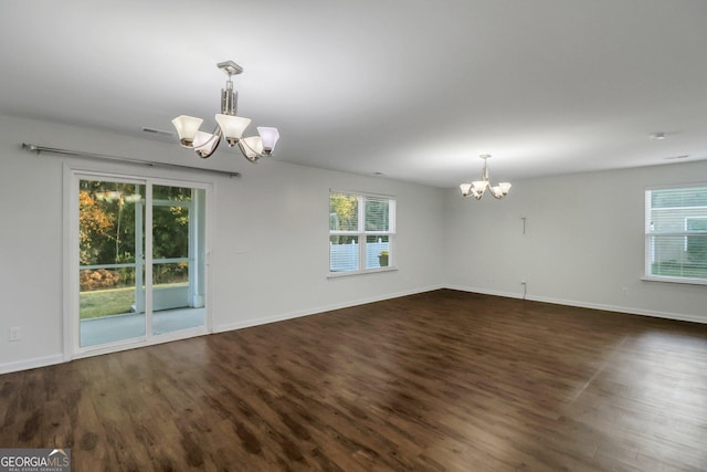 unfurnished room with a chandelier, dark hardwood / wood-style floors, and a wealth of natural light