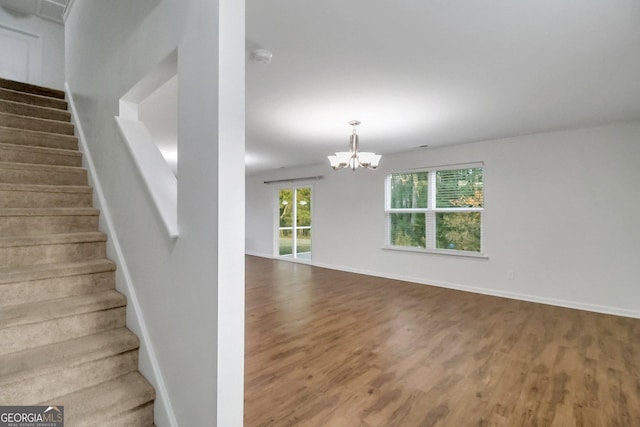 stairway with hardwood / wood-style flooring and a notable chandelier