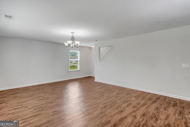 empty room featuring hardwood / wood-style flooring and an inviting chandelier