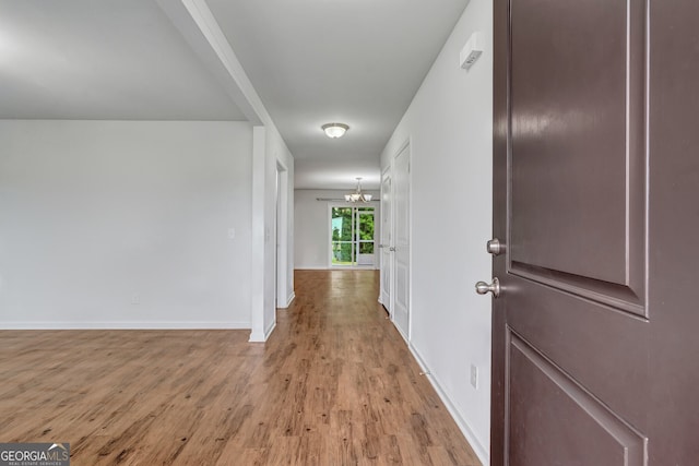 corridor with an inviting chandelier and light wood-type flooring