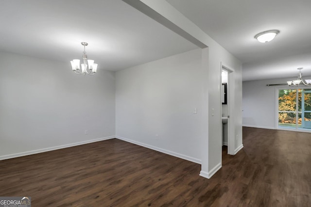 empty room with dark hardwood / wood-style floors and an inviting chandelier