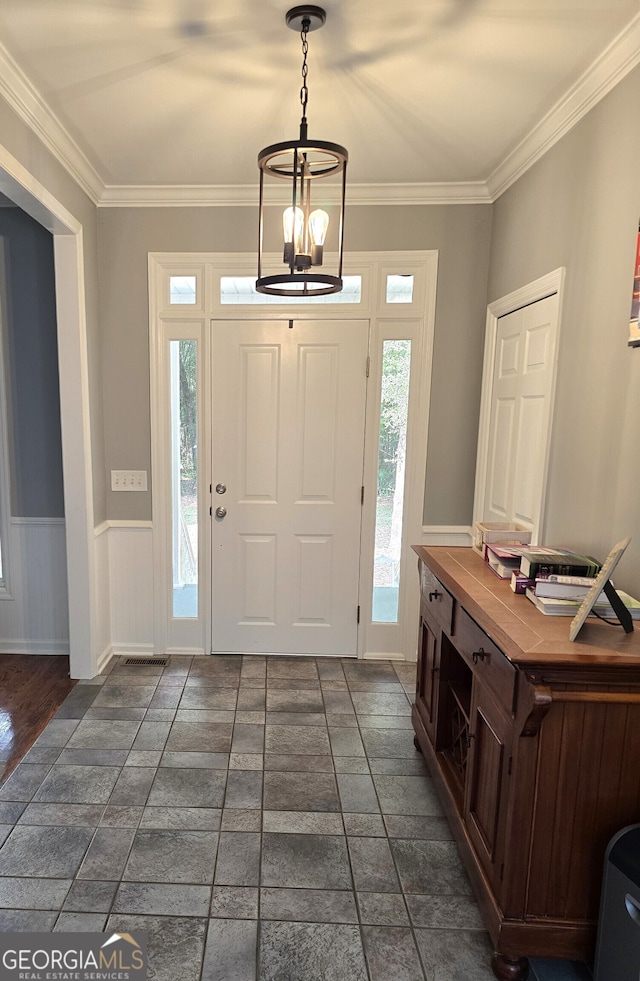 entryway featuring an inviting chandelier, crown molding, and dark wood-type flooring