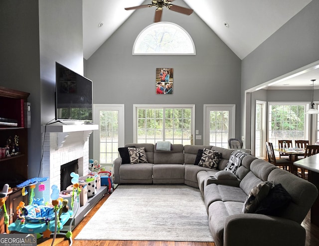 living room with wood-type flooring, a fireplace, ceiling fan, and high vaulted ceiling