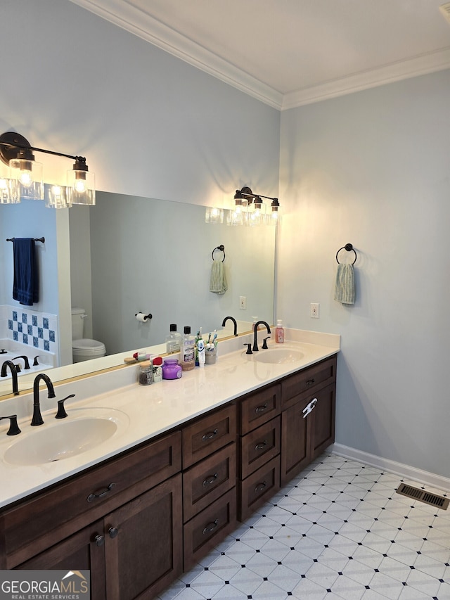 bathroom with ornamental molding, vanity, and toilet