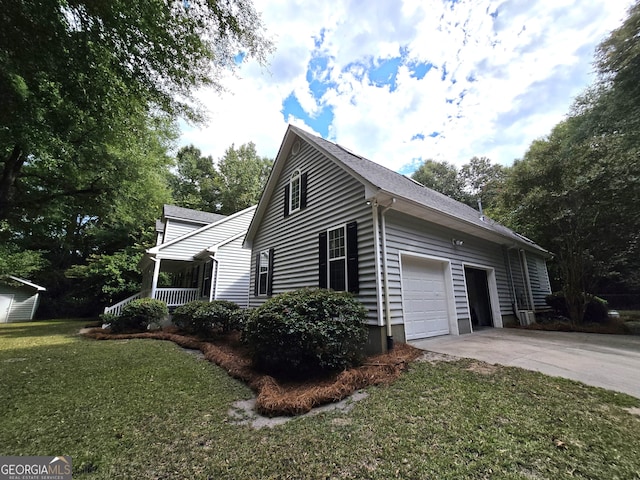 view of side of property featuring a lawn, covered porch, and a garage