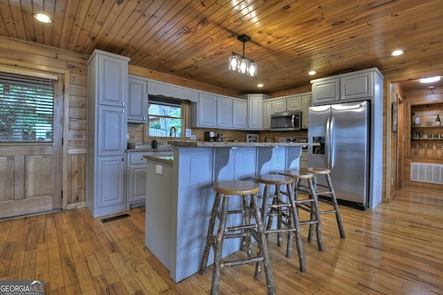 kitchen featuring lofted ceiling, light hardwood / wood-style flooring, stainless steel appliances, decorative light fixtures, and wooden ceiling